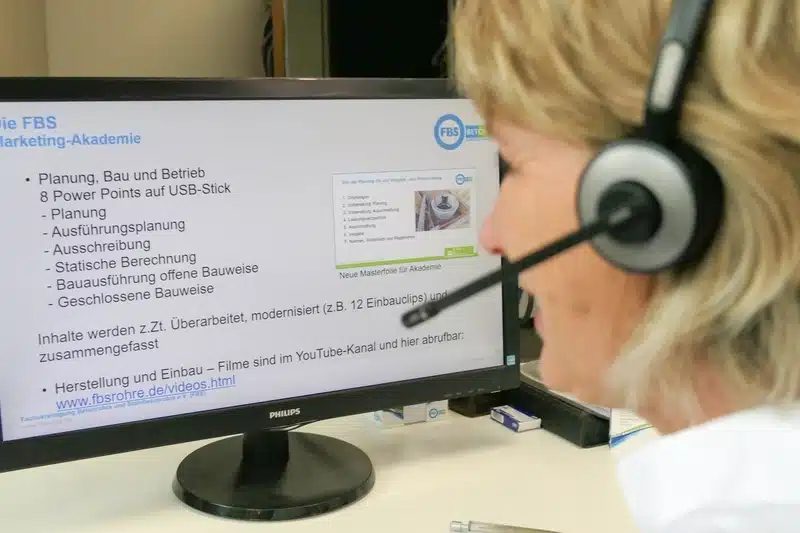 FBS Mitarbeiterin blickt mit Headset auf einen PC-Bildschirm