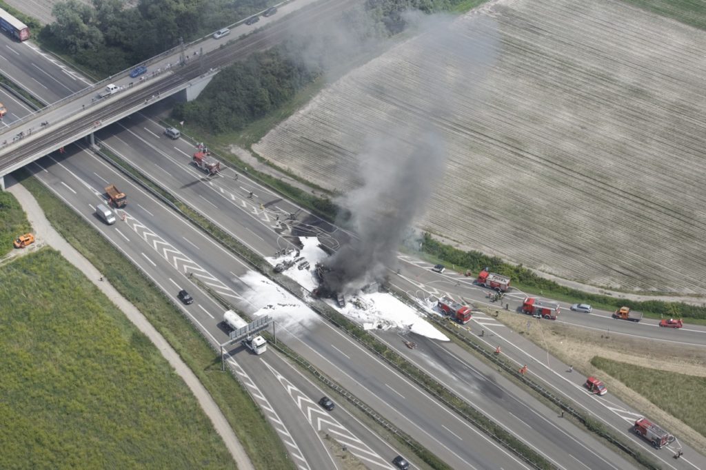 Luftaufnahme eines brennenden Fahrzeugs auf nach einem Unfall auf einer Autobahn